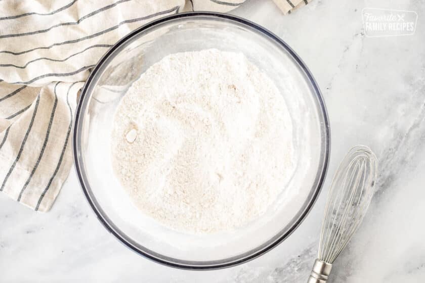 Glass bowl with whisked dry ingredients. Whisk on the side.