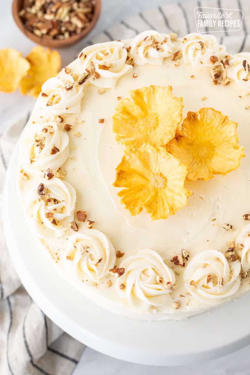 Hummingbird Cake topped with dried pineapple flowers and chopped roasted pecans.