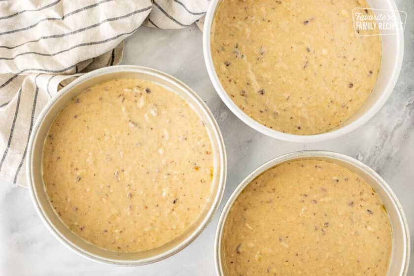 Three cake pans with cake batter.