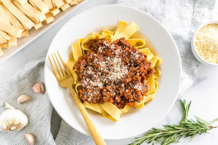 A bowl of Pappardelle Bolognese topped with parmesan cheese