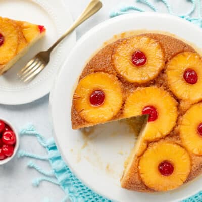 Cake stand with Pineapple Upside Down Cake missing a slice. Slice of Pineapple Upside Down Cake on a plate.