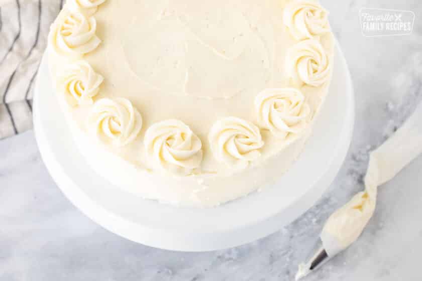 Pipping cream cheese decorative swirls on top of Hummingbird Cake.