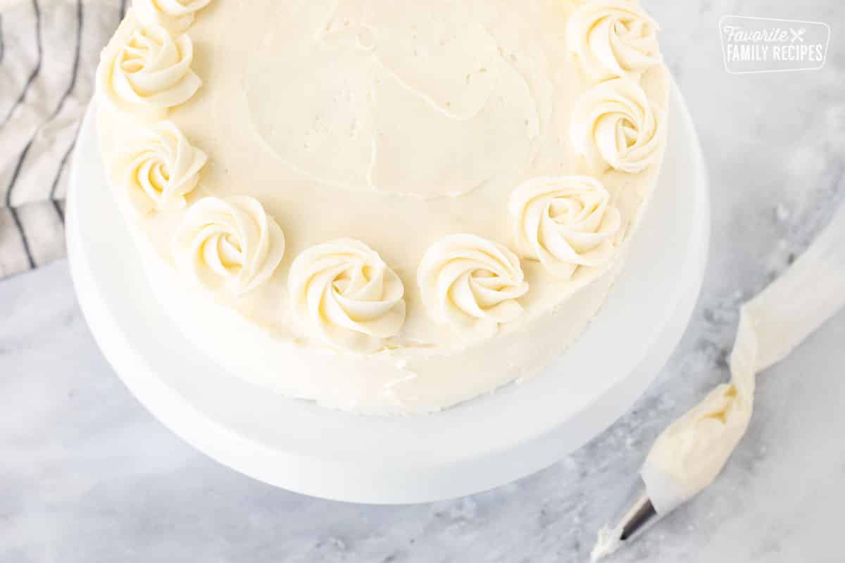 Pipping cream cheese decorative swirls on top of Hummingbird Cake.