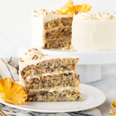 Slice of three layered Hummingbird Cake on a plate with a dried pineapple flower.