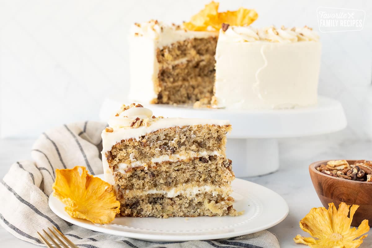 Slice of three layered Hummingbird Cake on a plate with a dried pineapple flower.