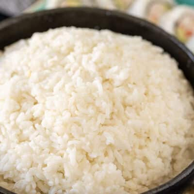 Bowl of Sushi Rice. Sushi in the background.