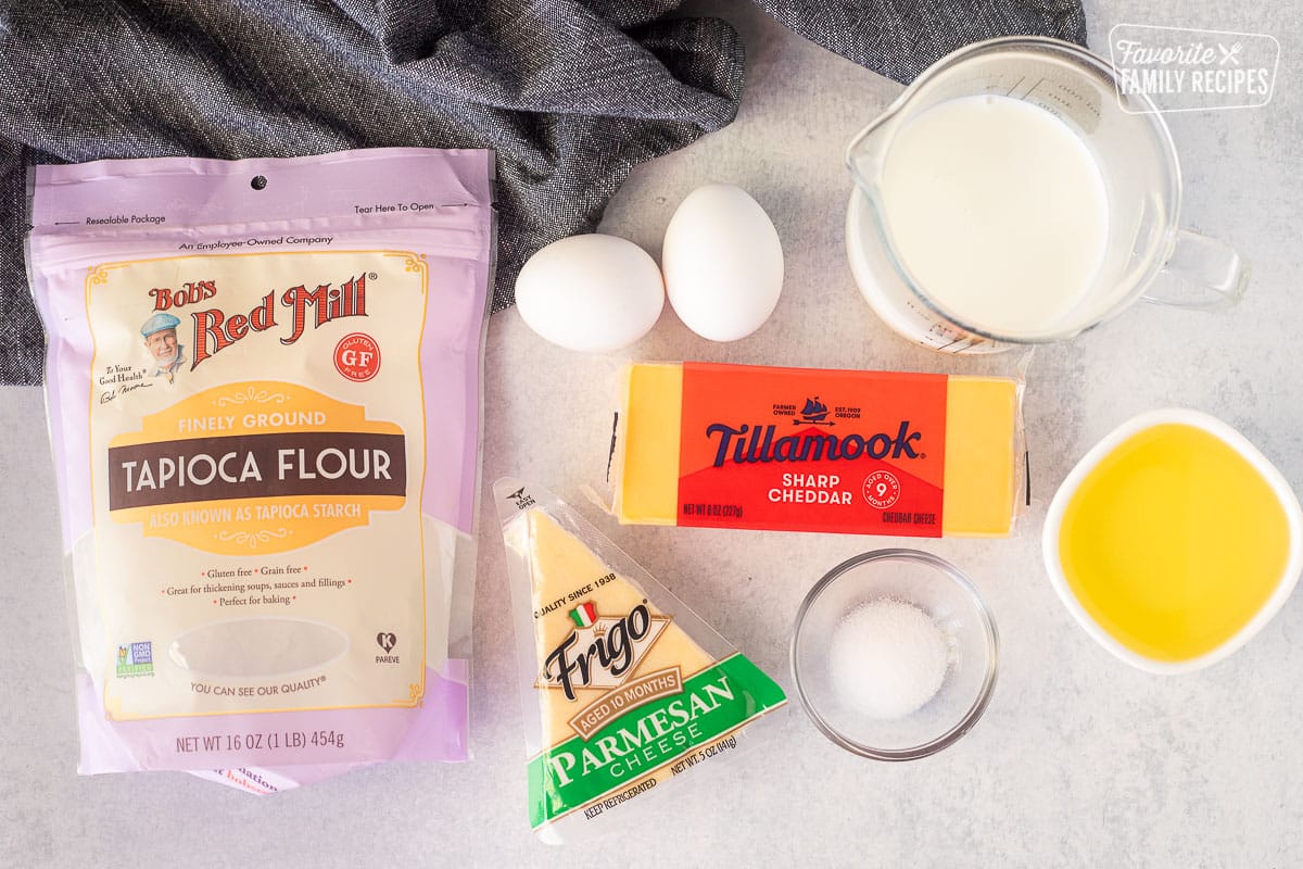 Ingredients to make Brazilian Cheese Bread including tapioca flour, sharp cheddar cheese, parmesan cheese, salt, oil, eggs and whole milk.