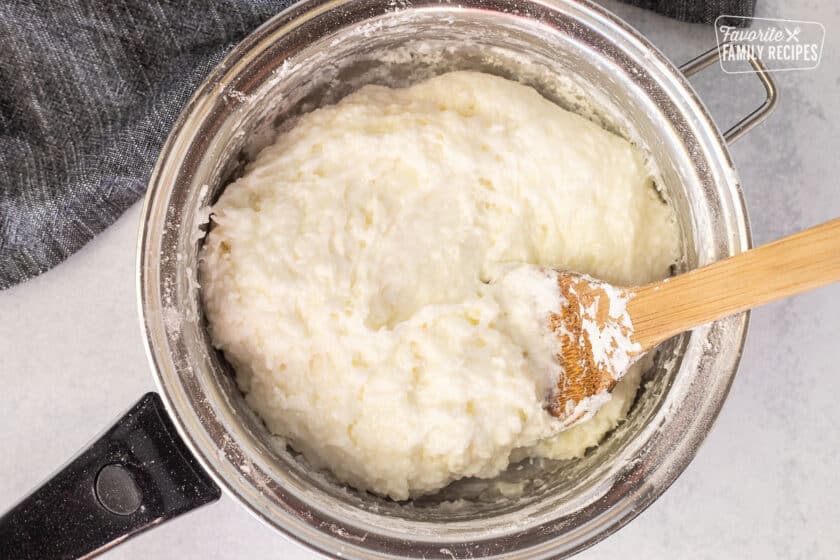 Wooden spoon in saucepan with thick white tapioca base.