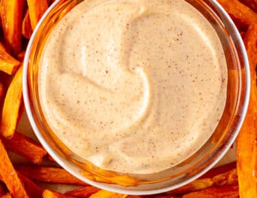 Plate of Dipping sauce surrounded by sweet potato fries.