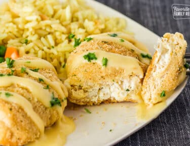 Cut piece of Chicken Roll up with a fork resting on a plate. Rice on the side.