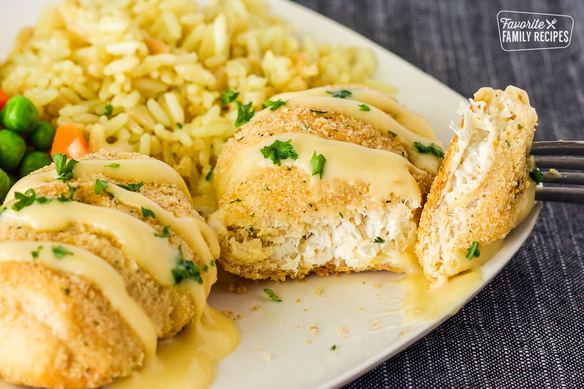 Cut piece of Chicken Roll up with a fork resting on a plate. Rice on the side.