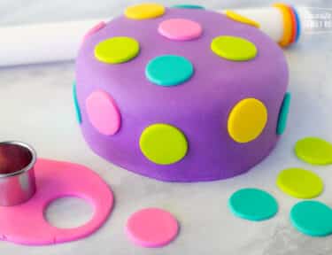 Decorated Fondant Cake with colored polka dots. Fondant roller on the side. Small rolled out pink fondant with circle cutter.