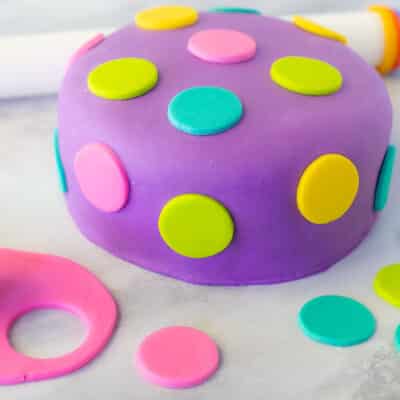 Decorated Fondant Cake with colored polka dots. Fondant roller on the side. Small rolled out pink fondant with circle cutter.