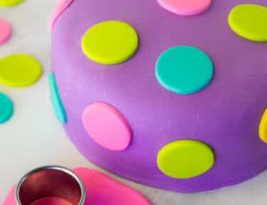 Decorated Fondant Cake with colored polka dots. Fondant roller on the side. Small rolled out pink fondant with circle cutter.