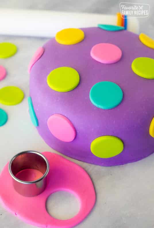 Decorated Fondant Cake with colored polka dots. Fondant roller on the side. Small rolled out pink fondant with circle cutter.