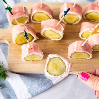 A ham and pickle roll up being picked up by a toothpick