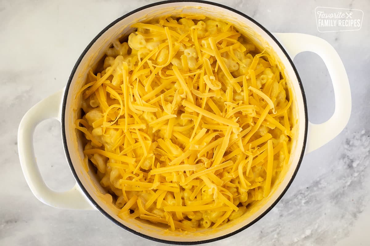 Shredded cheese on top of pasta in a dutch oven.