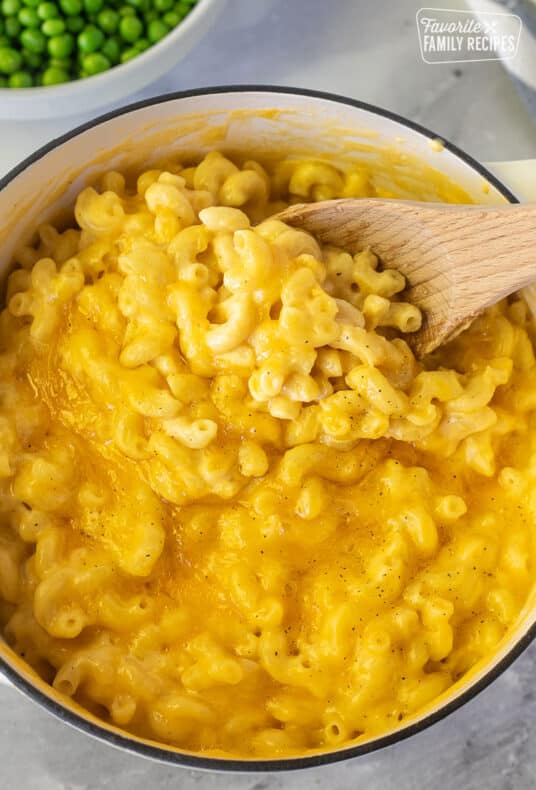 Scooping homemade Mac and cheese with a wooden spoon.