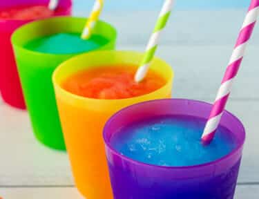 Blue and pink slushie in cups with colorful straws.