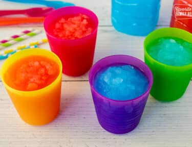 Four colorful cups of slushie with straws on the side.