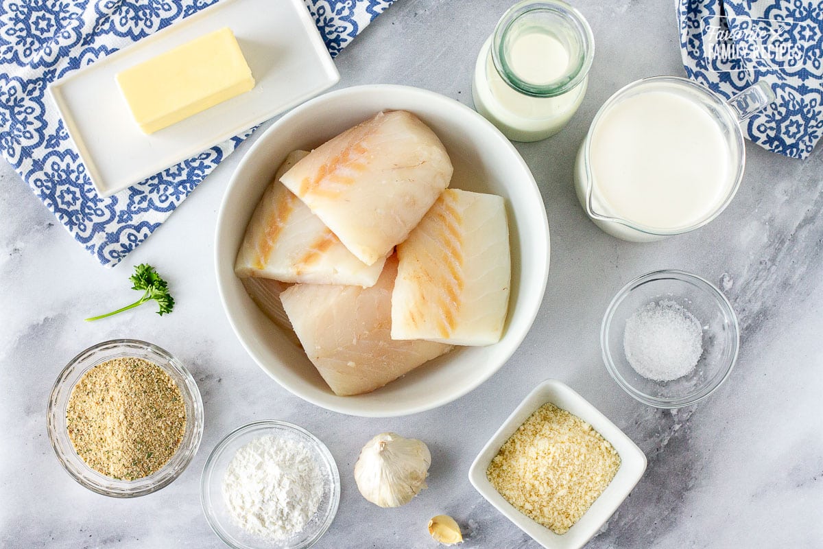 Ingredients to make Baked Cod in Cream Sauce including cod, butter, cream, milk, salt, bread crumbs, flour, garlic and parmesan cheese.