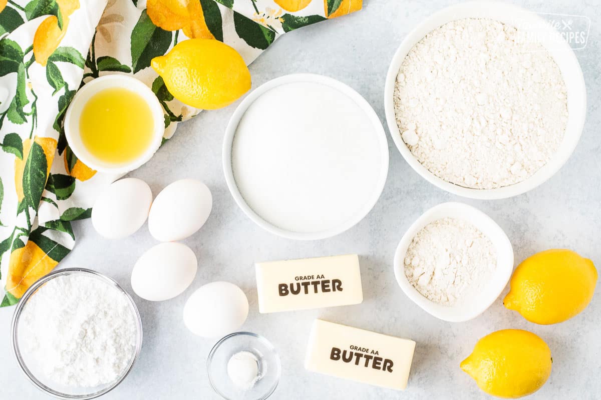 Ingredients to make Lemon Bars including flour, sugar, butter, eggs, lemons, baking powder, lemon juice, powdered sugar.