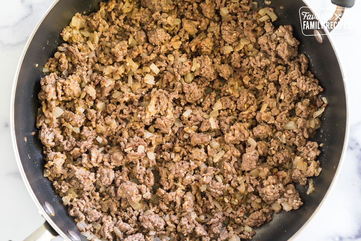 browned beef and sauteed onions in a skillet