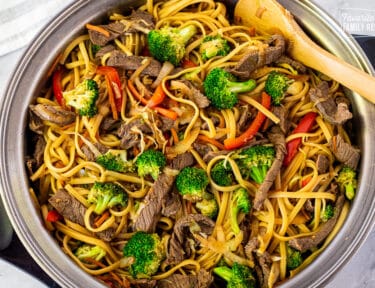 Skillet of Steak Stir Fry with a wooden spoon.