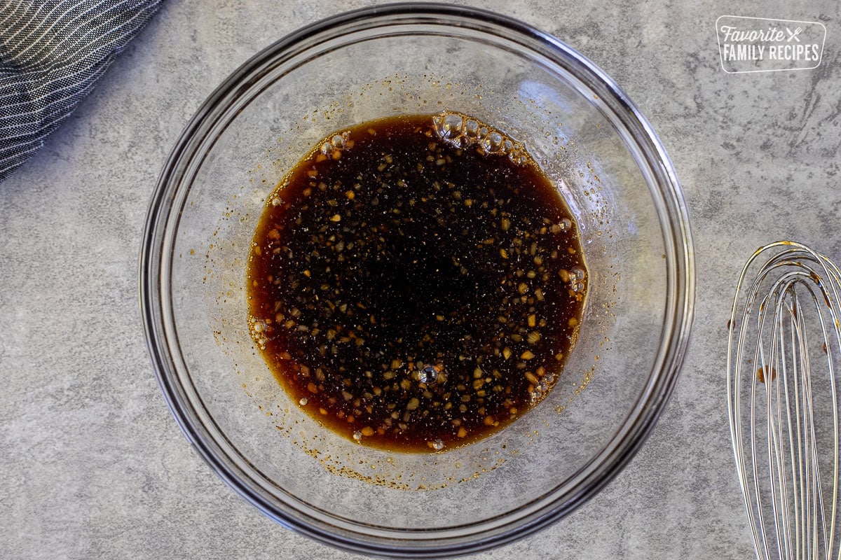 Glass bowl with soy sauce mixture. Whisk on the side.