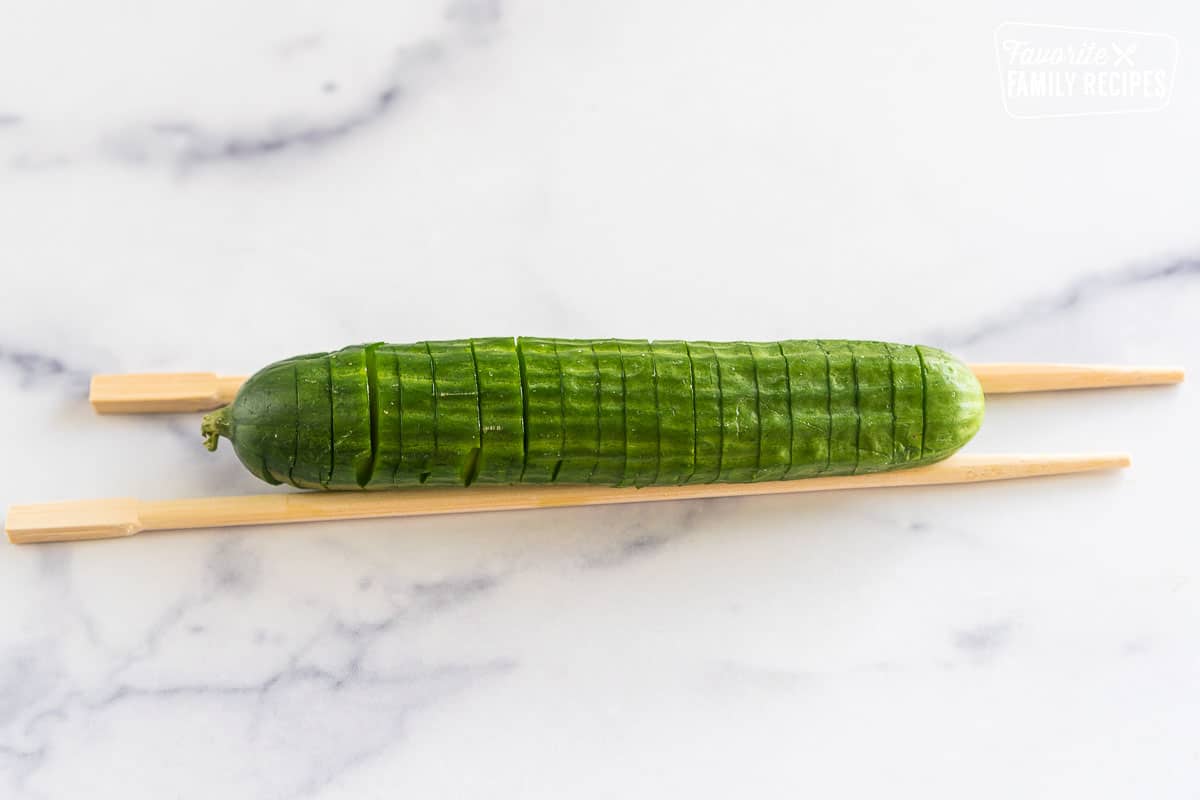 mini cucumber between two chopsticks cut in straight slices