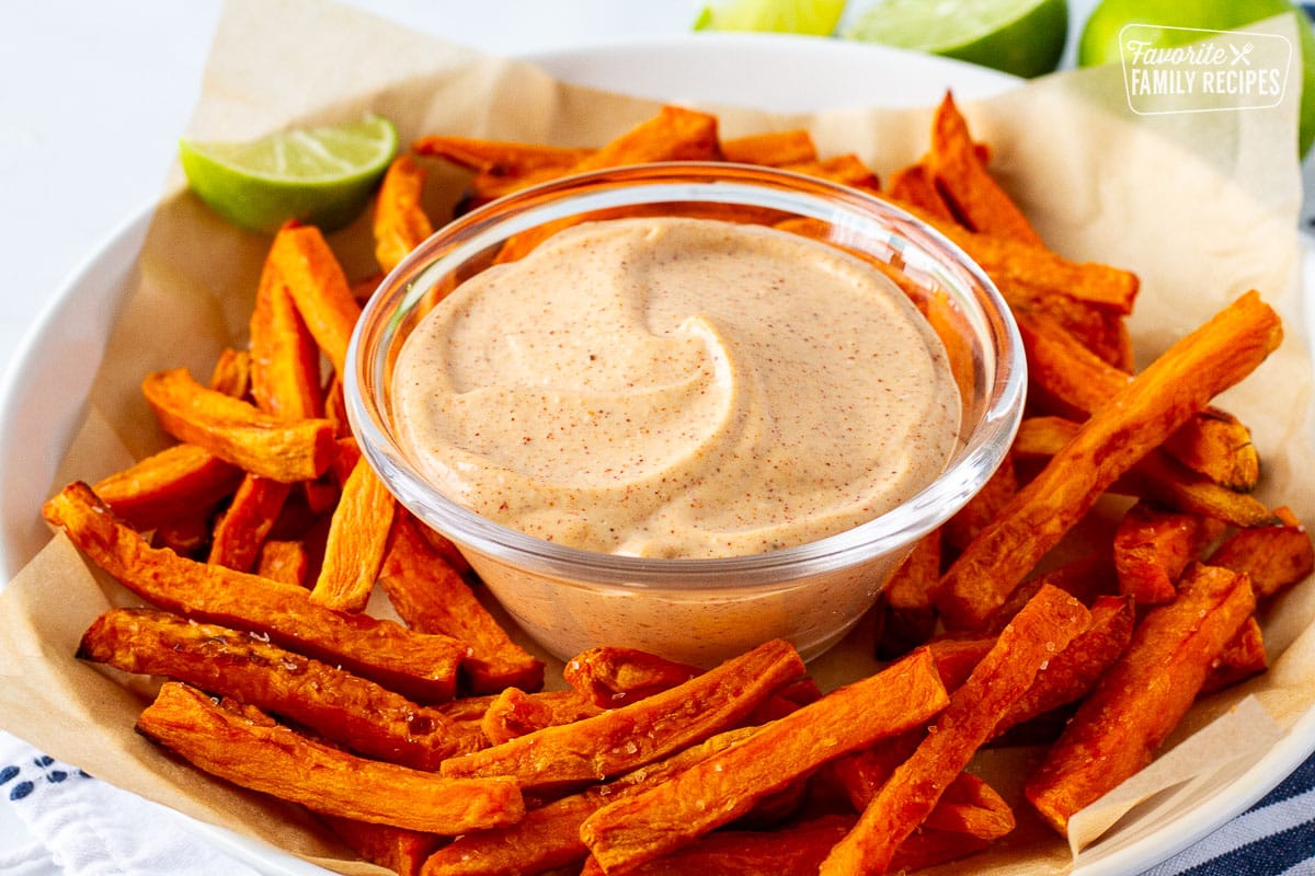 Plate of sweet potato fries with dipping sauce in the center.