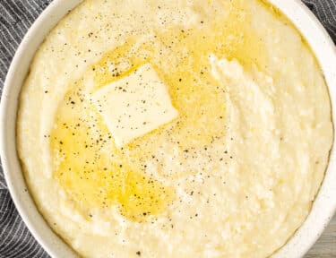 Bowl of Grits with butter melting on top and pepper.