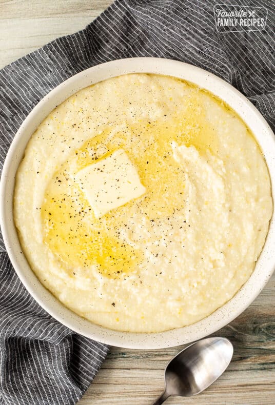 Bowl of Grits with butter melting on top and pepper.