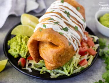 Large Chicken Chimichanga on a plate with toppings.