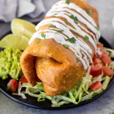 Large Chicken Chimichanga on a plate with toppings.