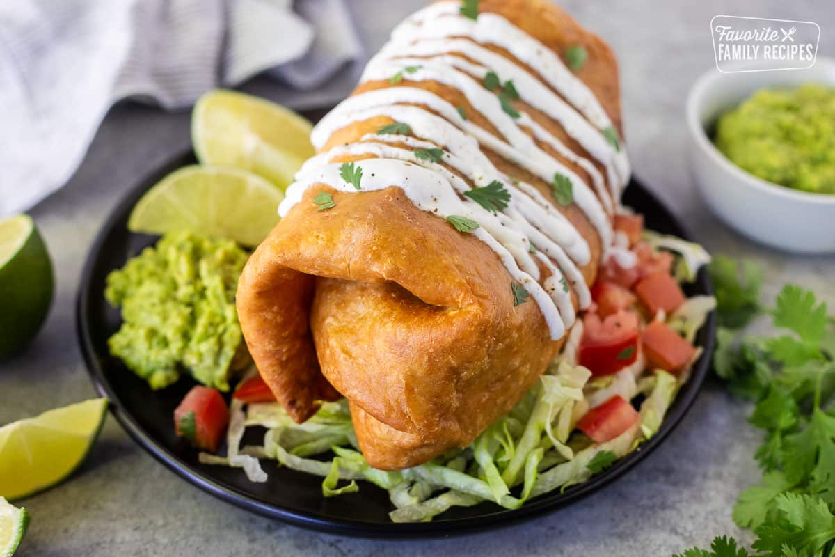 Large Chicken Chimichanga on a plate with toppings.