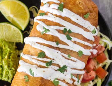 Chicken Chimichanga with sour cream drizzled on top and cilantro.