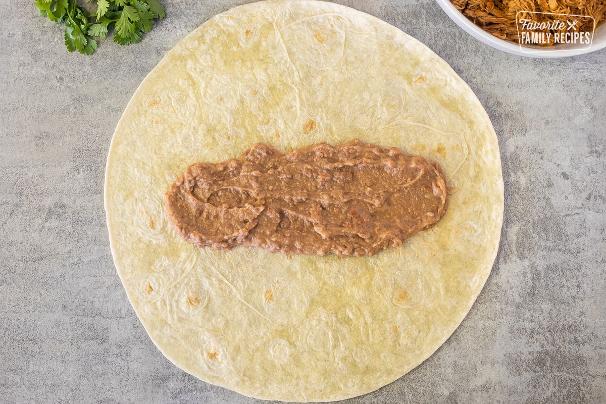 Refried beans spread on a flour tortilla.