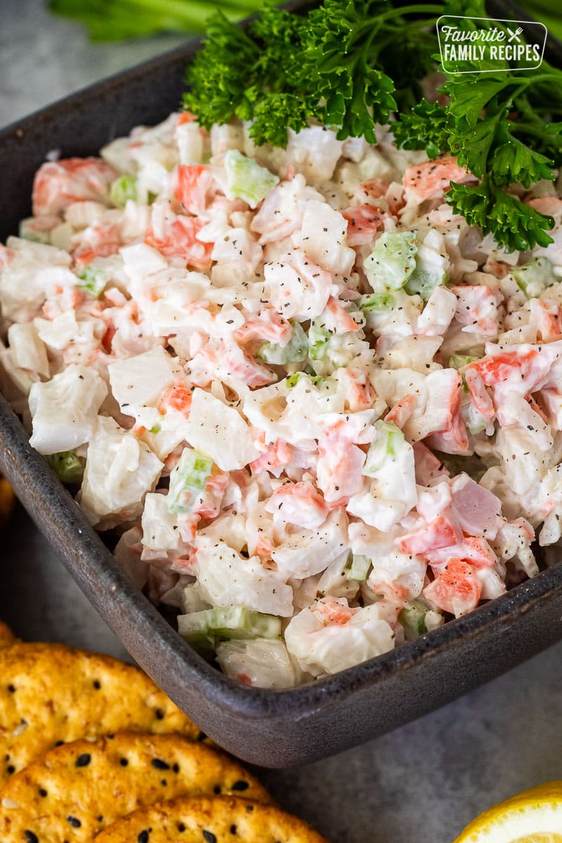 Cold Crab Dip in a bowl garnished with parsley. Crackers on the side.