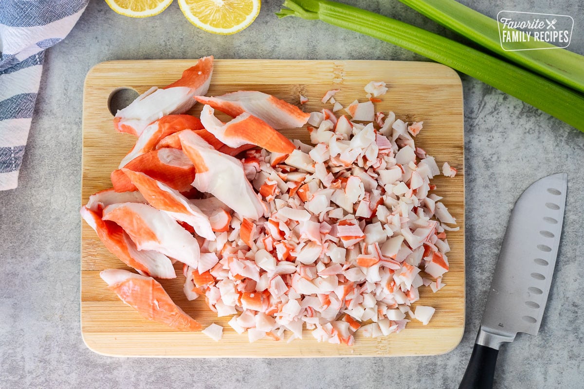 Cutting up imitation crab on a board. Knife on the side.