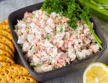 Bowl of Cold Crab Dip Recipe garnished with parsley and crackers on the side.