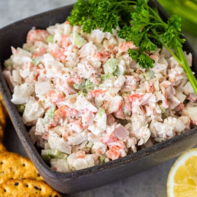 Bowl of Cold Crab Dip Recipe garnished with parsley and crackers on the side.