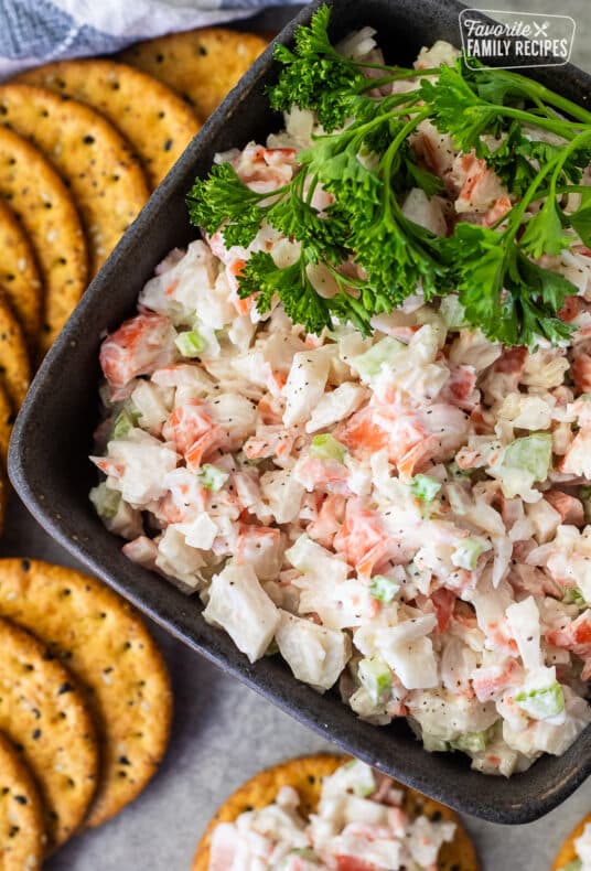 Cold Crab Dip in a bowl with parsley on top and crackers on the side.