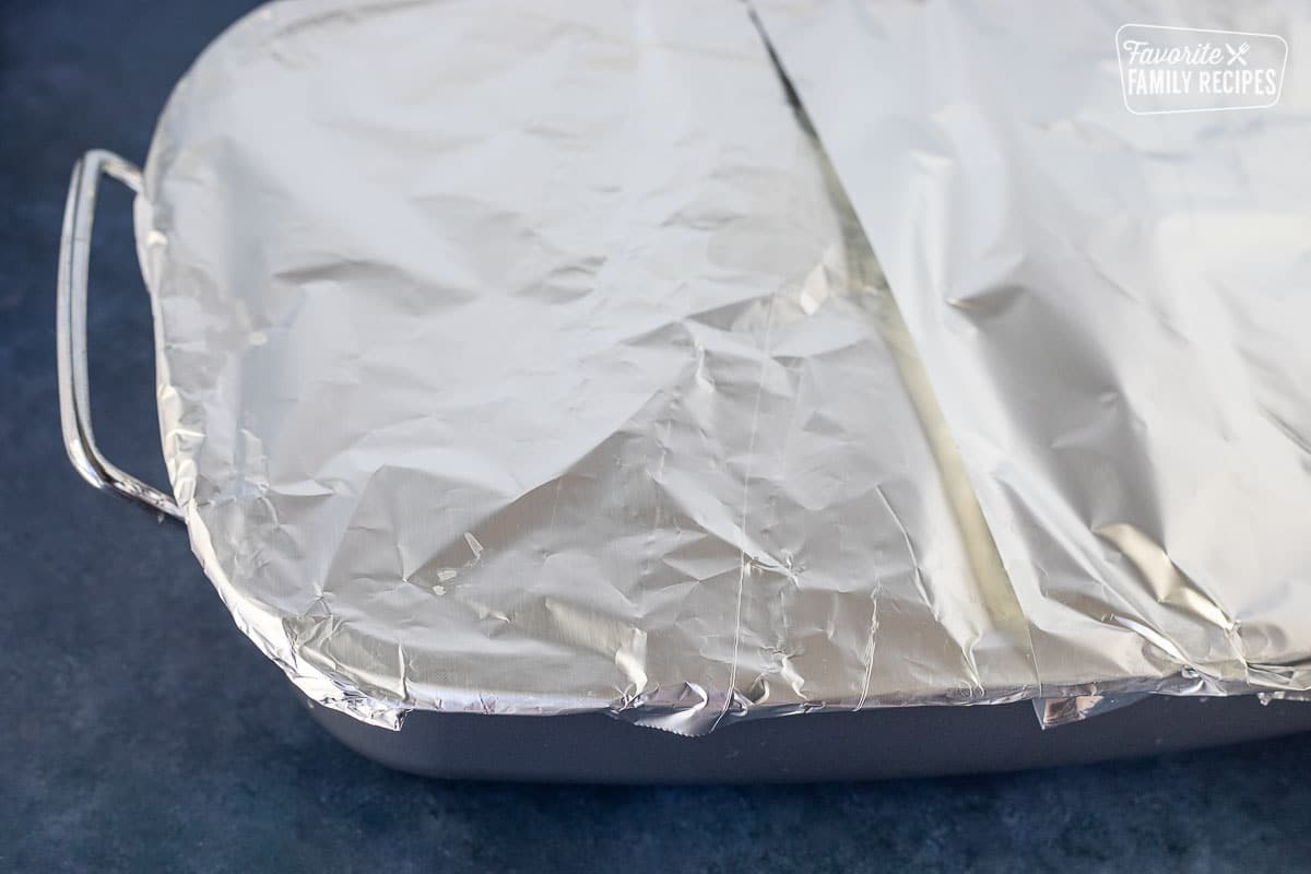 Covering roasting pan with aluminum foil.