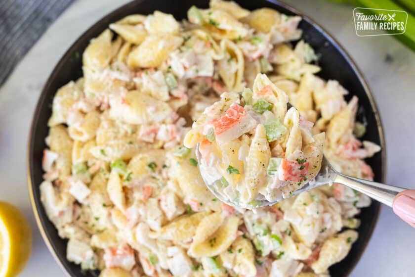 Hand holding a spoon of Crab Pasta Salad.