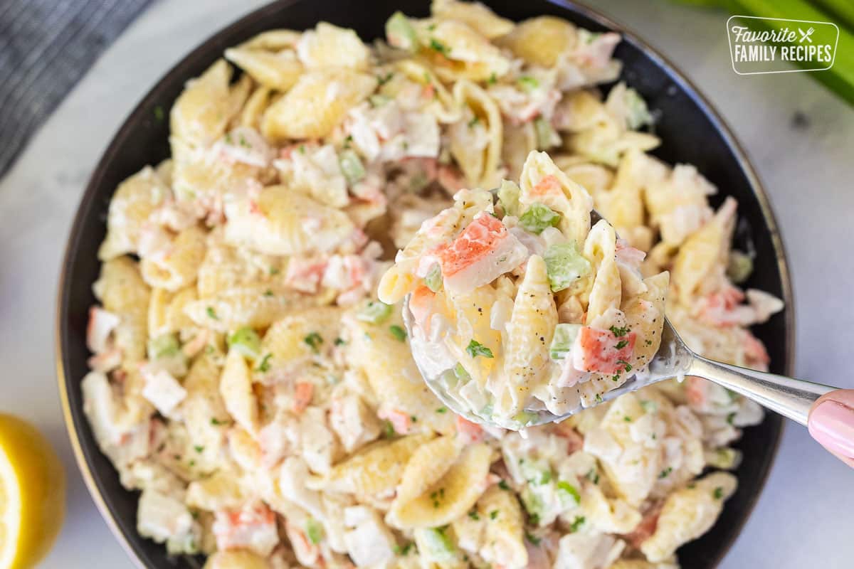Hand holding a spoon of Crab Pasta Salad.