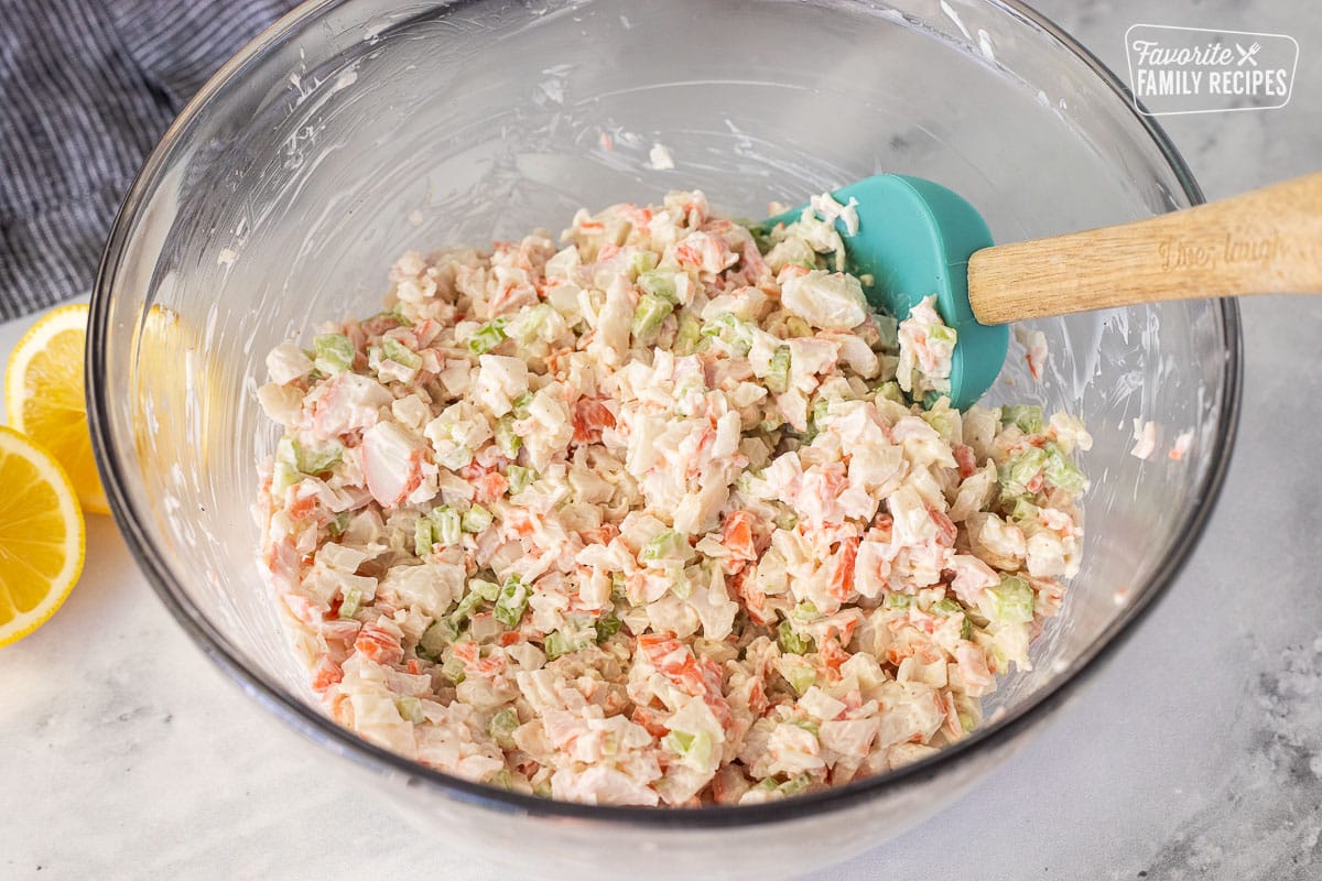 Mixing bowl with crab salad mixture with spatula.