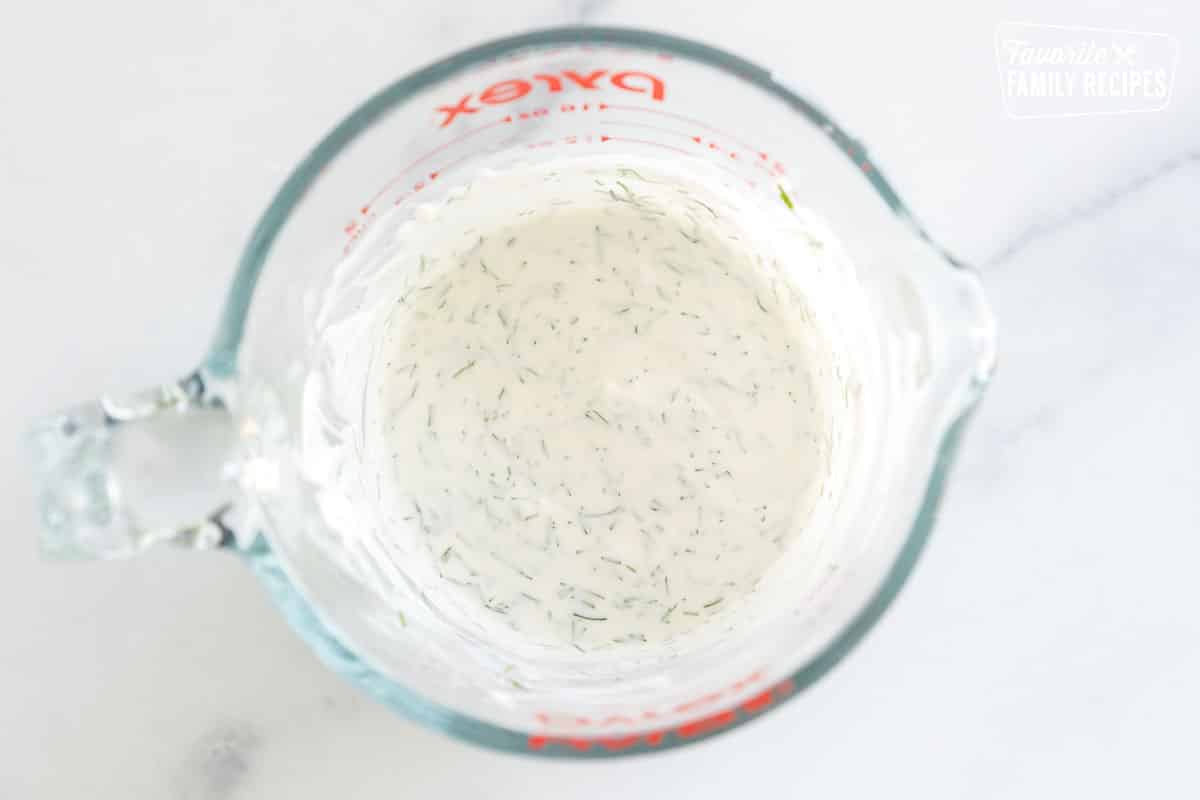 sour cream dill dressing in a glass measuring cup