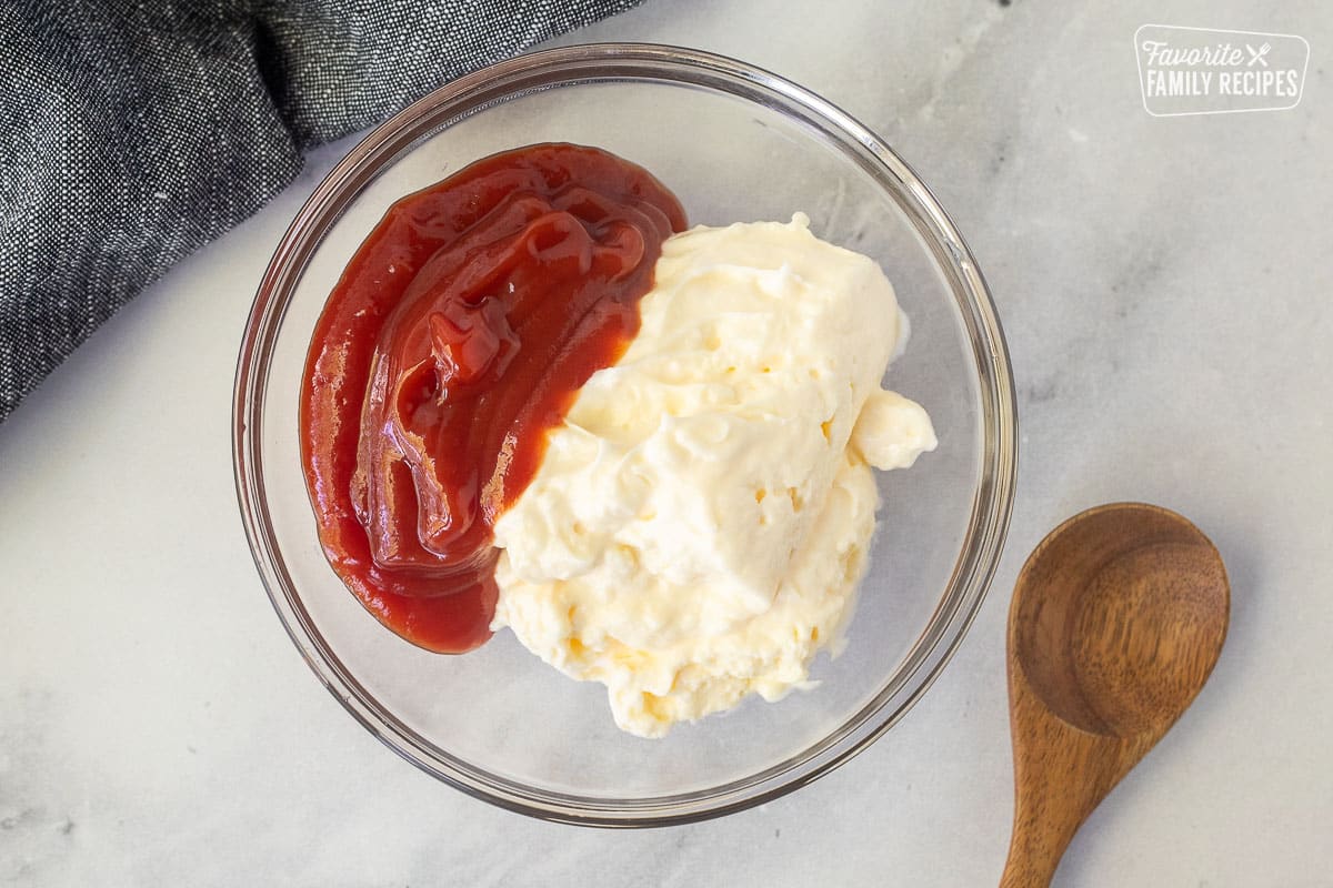 Glass bowl with ketchup and mayonnaise. Spoon on the side.