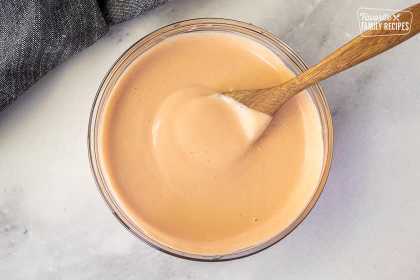 Wooden spoon resting in a glass bowl of fry sauce.